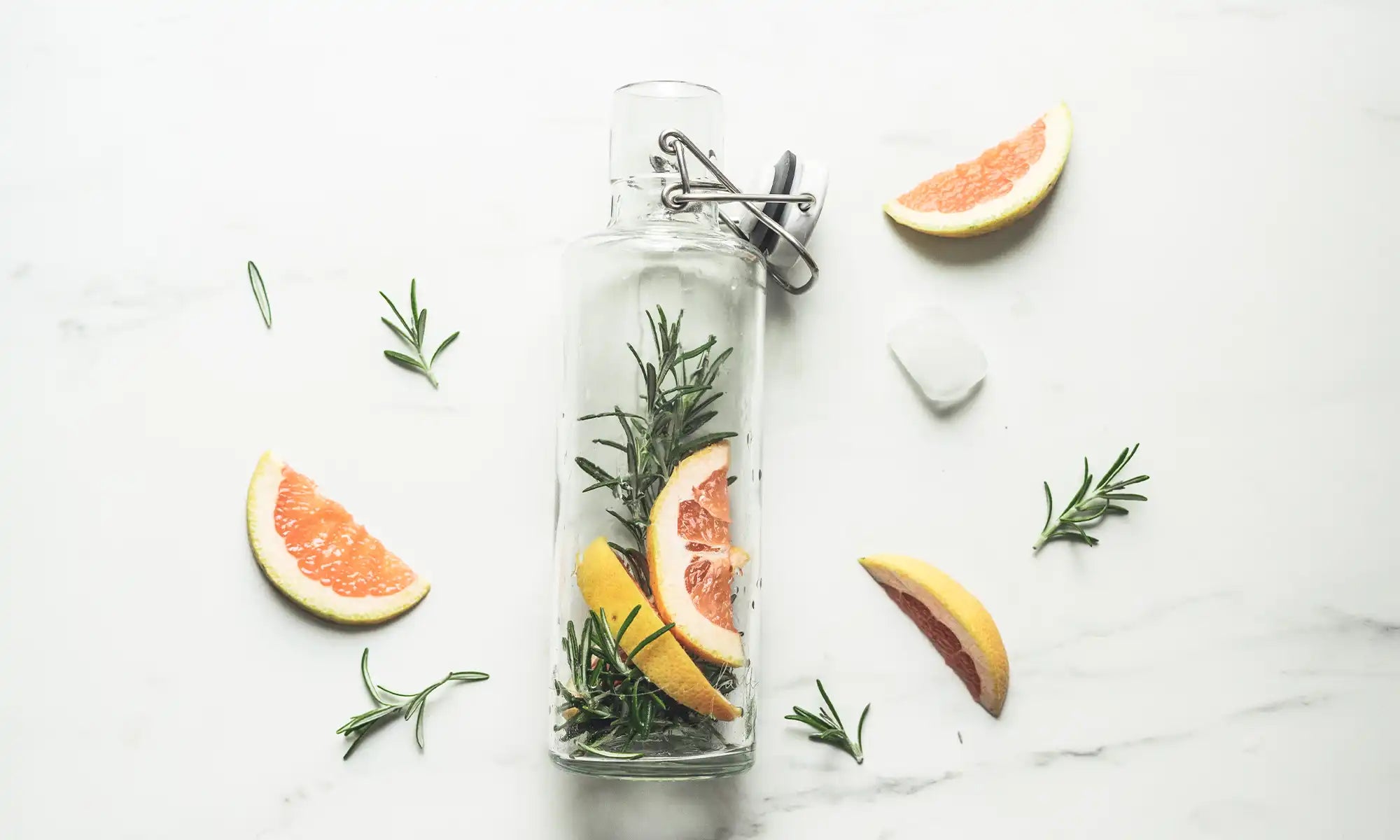 Trinkflasche aus Glas mit infused Water mit Rosmarin und Grapefruit