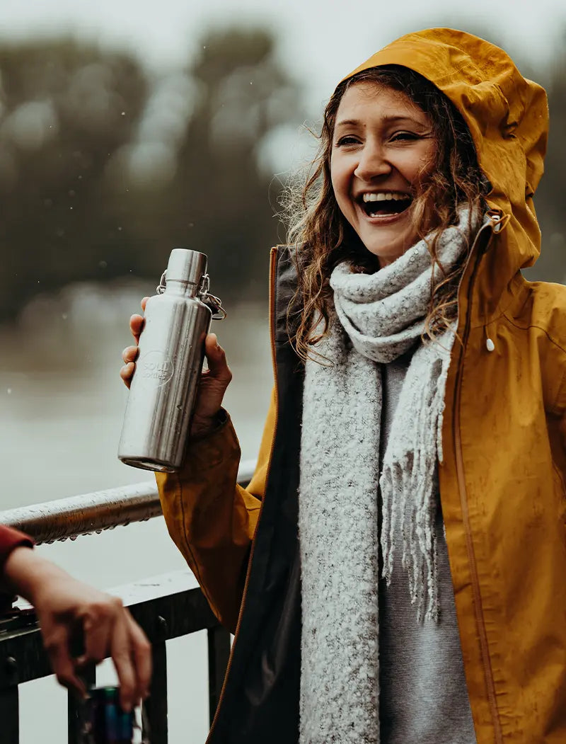 Frau mit Regenjacke mit soulbottle Trinkflasche aus Edelstahl