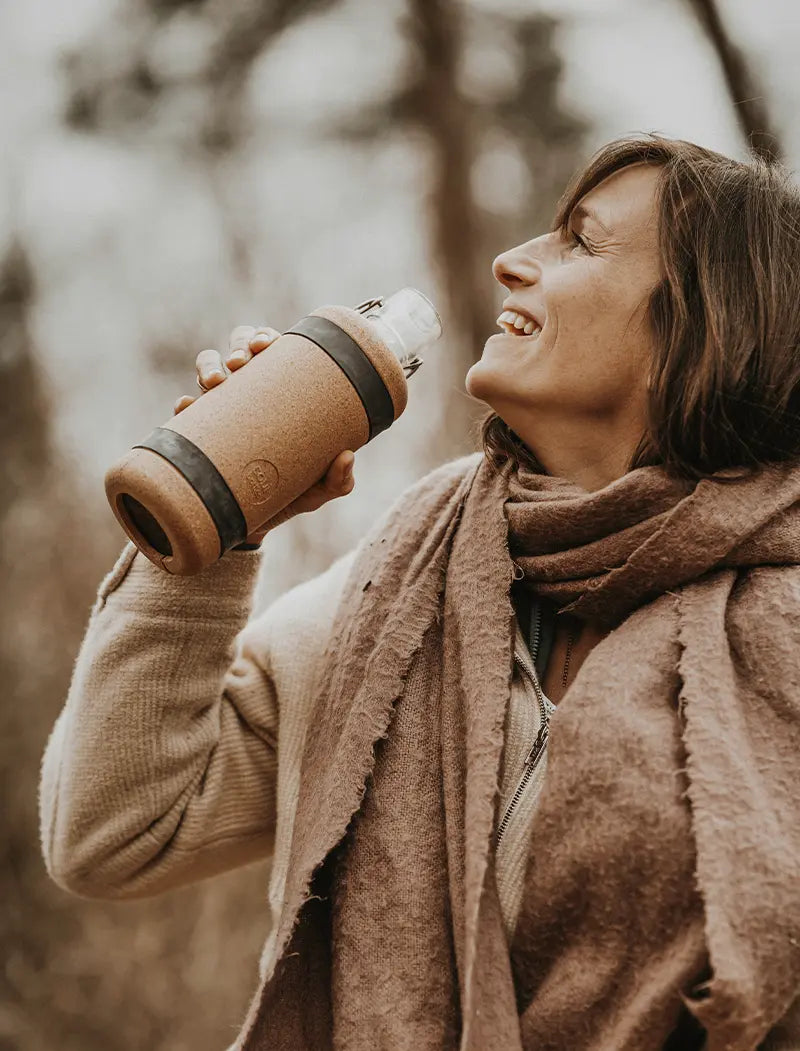 Frau mit Trinkflasche aus Glas mit Korkschutz