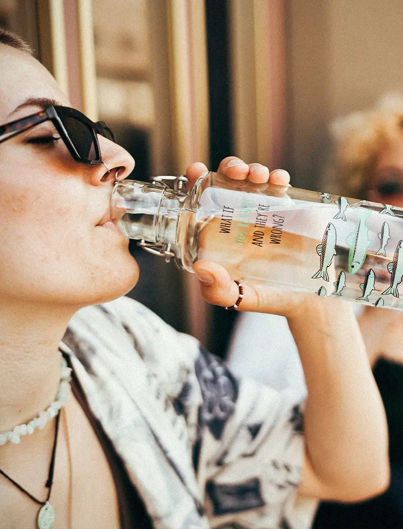 Frau trinkt aus Trinkflasche mit Fisch-Motiv