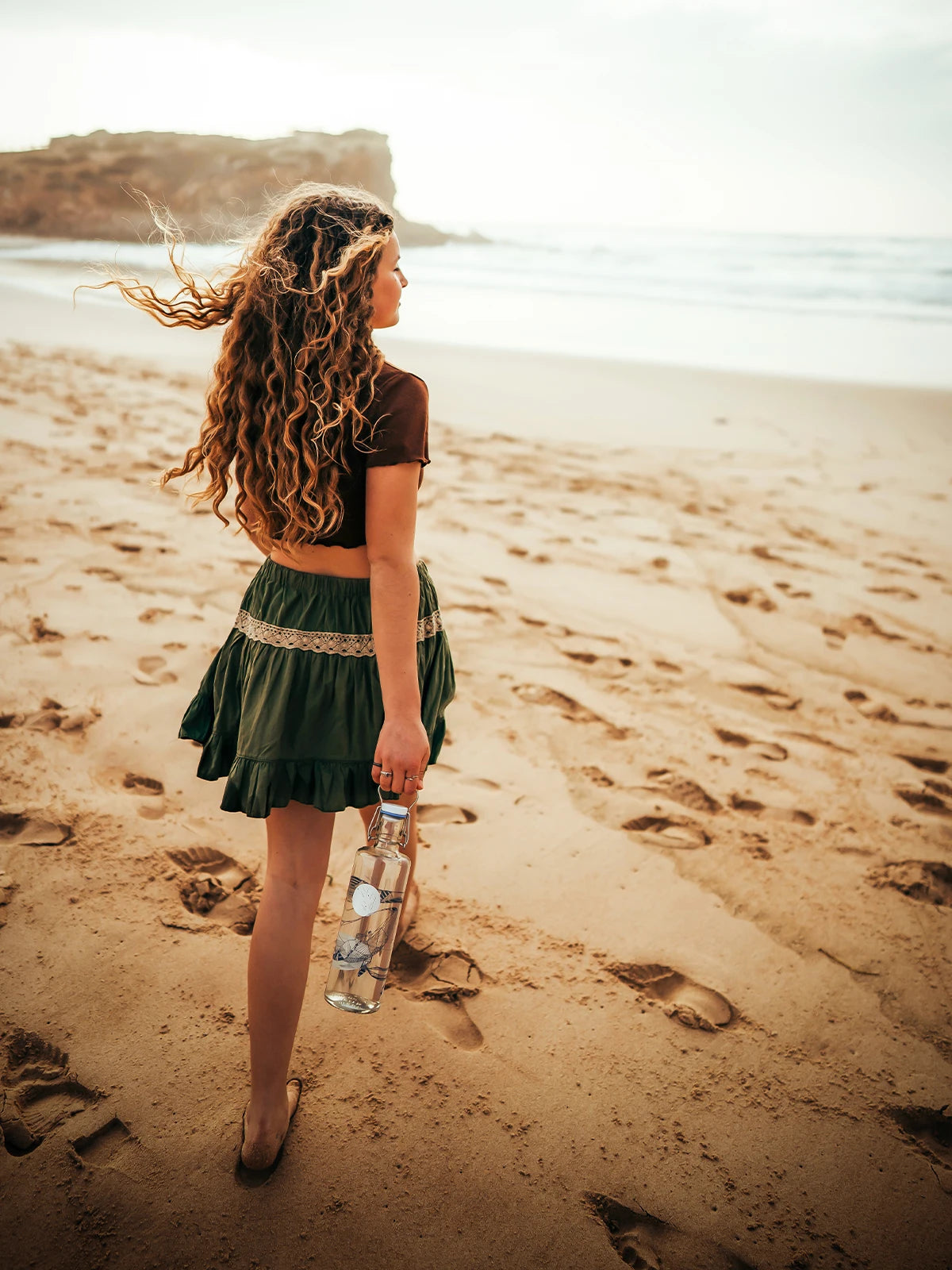 Frau mit Trinkflasche aus Glas und Motiv souldiver am Strand