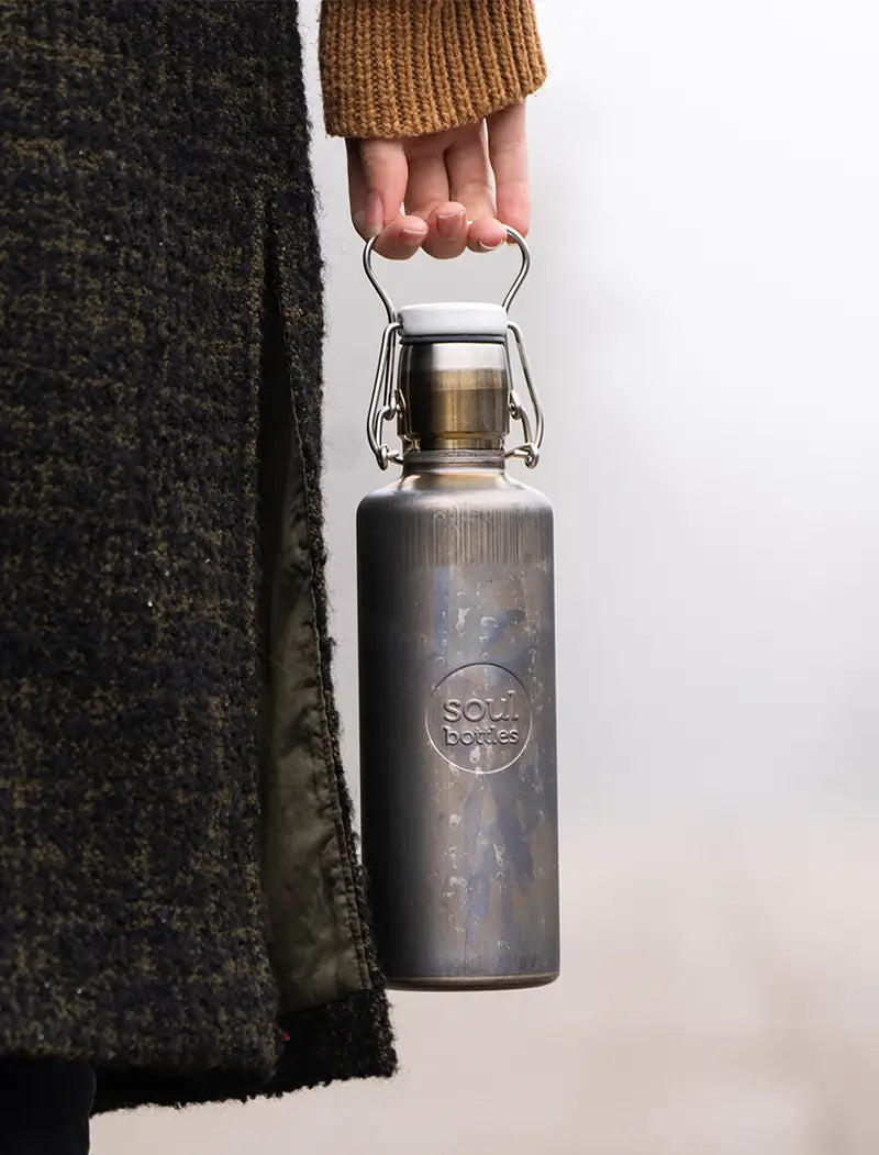 Frau mit isolierter Trinkflasche aus Edelstahl im Industrial-Look