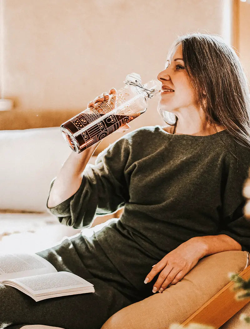 Frau trinkt aus Trinkflasche mit Sesamstrasse Motiv