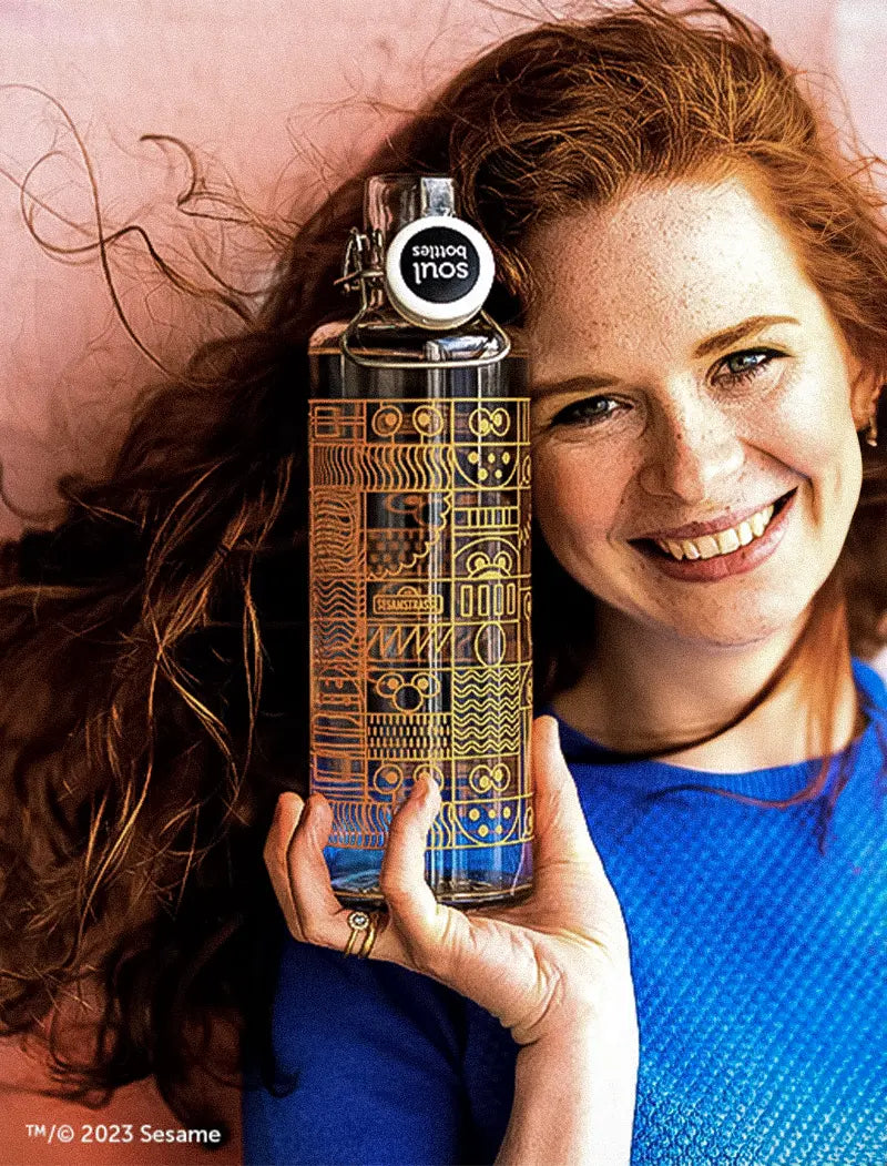 Frau mit roten Haaren mit Trinkflasche in der Hand mit Sesamstrasse Motiv