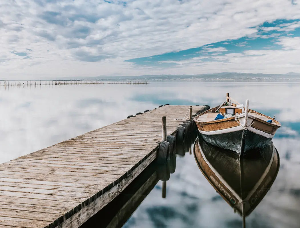 Holzboot an Holznleger auf ruhigem Wasser