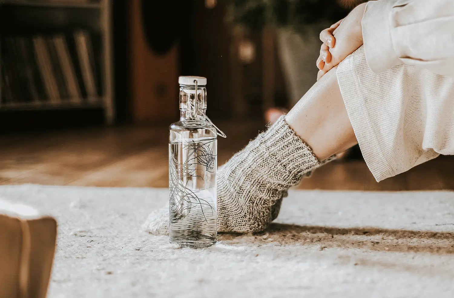 Trinkflasche aus Glas mit Meeresmotiv Quallen steht auf Teppich