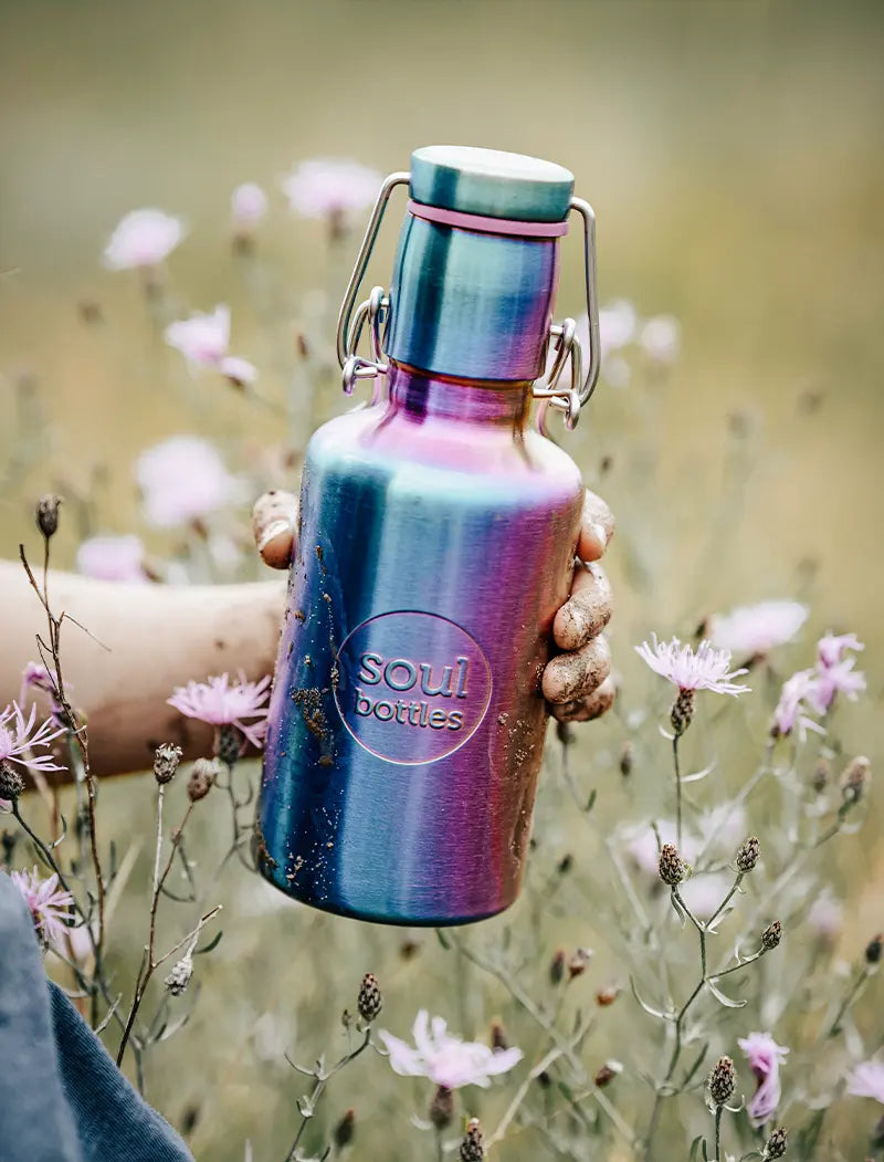 Einwandige Trinkflasche aus Edelstahl im Regenbogenlook auf Feld