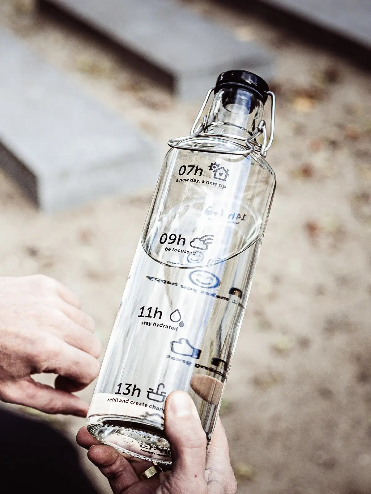 Mann hält Trinkflasche aus Glas in der Hand