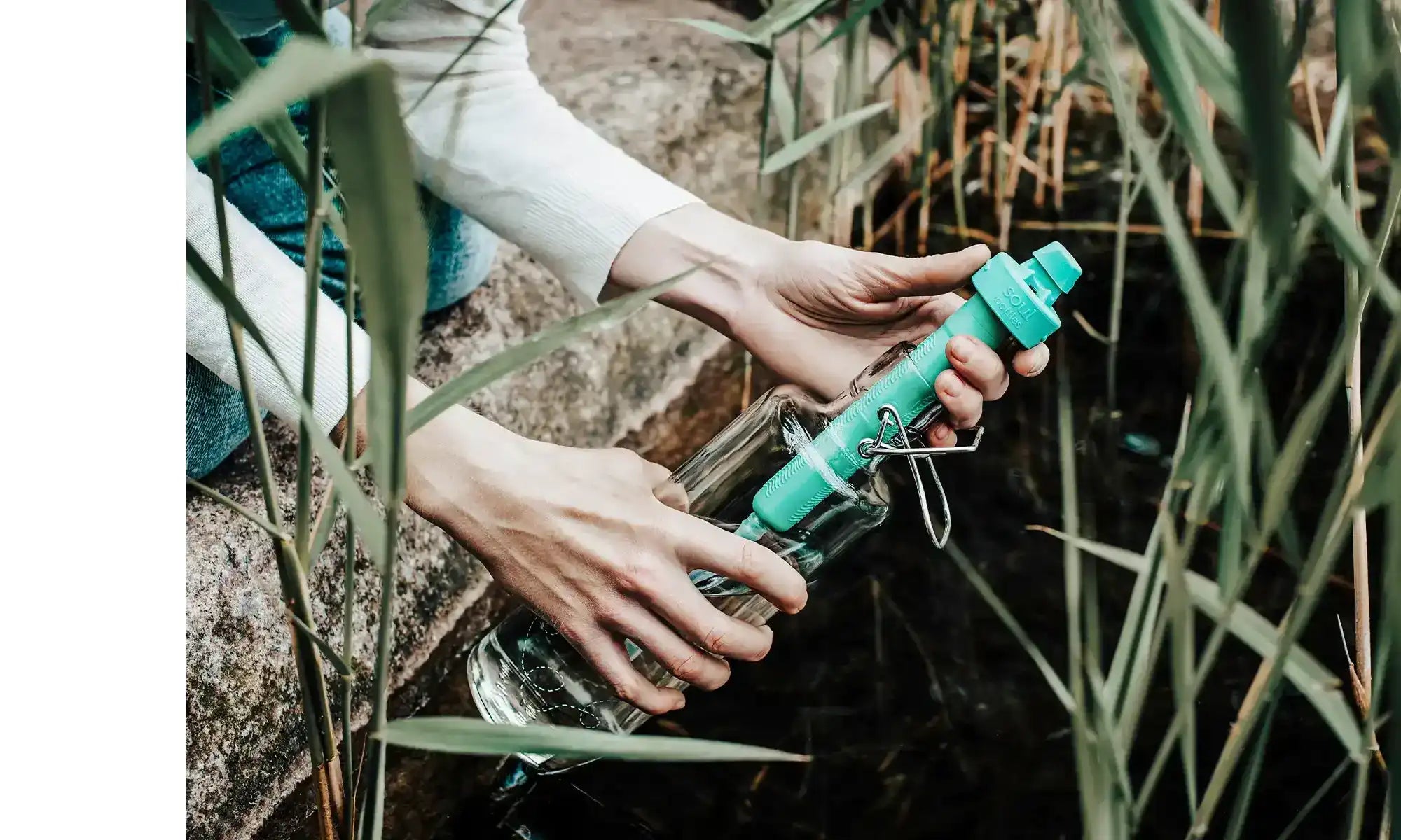 Frau mit Glastrinkflasche und Wasserfilter am See